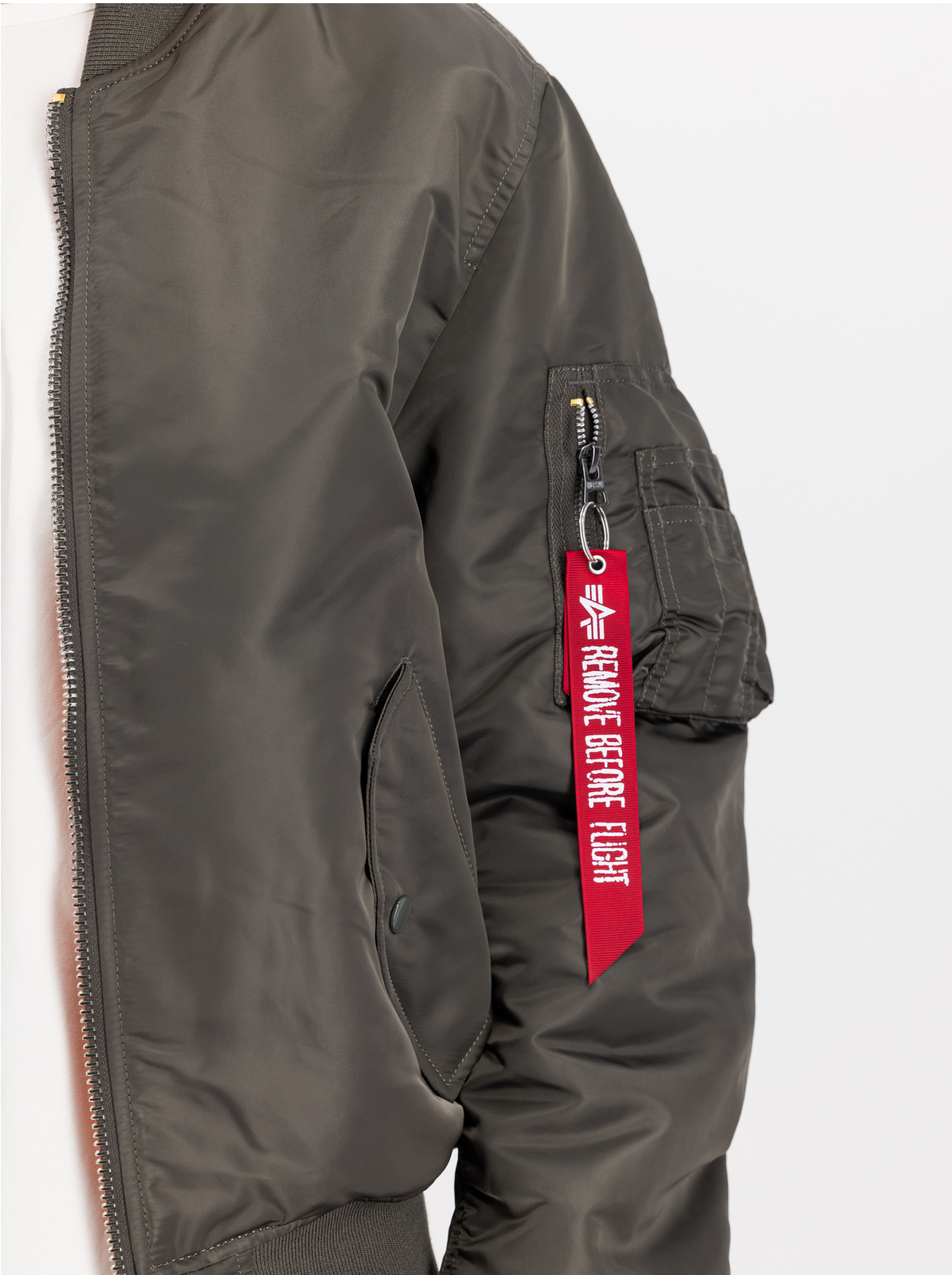 Ärmeltasche einer Alpha-Industries-Bomberjacke mit rotem Remove-Before-Flight-Band