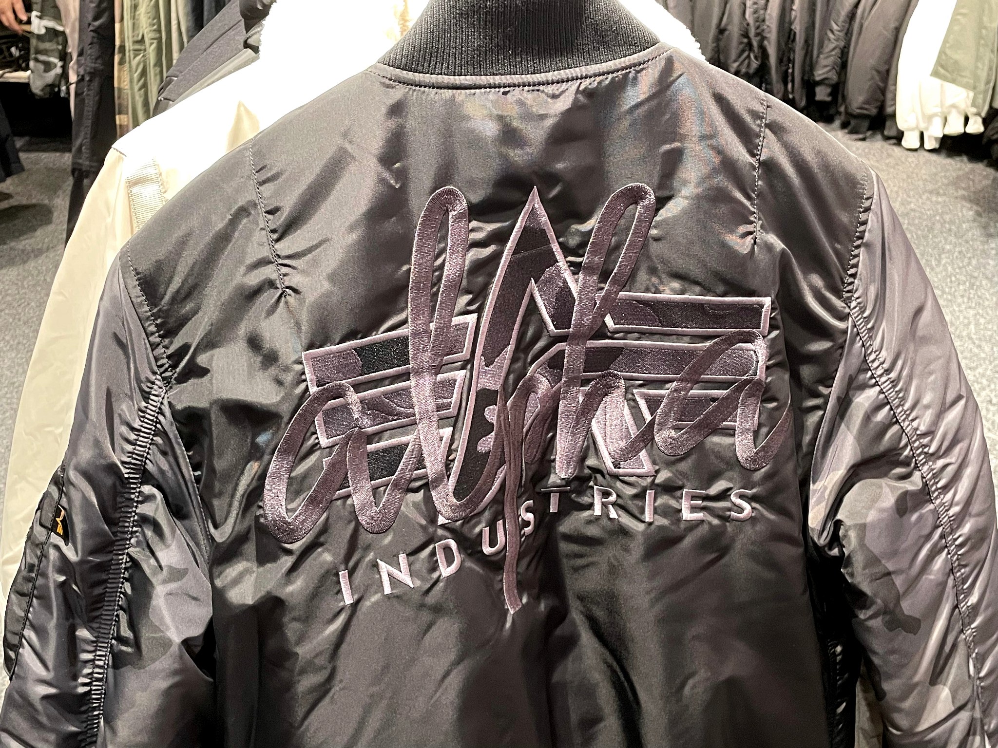 Rückseite einer Alpha-Industries-Bomberjacke mit gesticktem Schriftzug