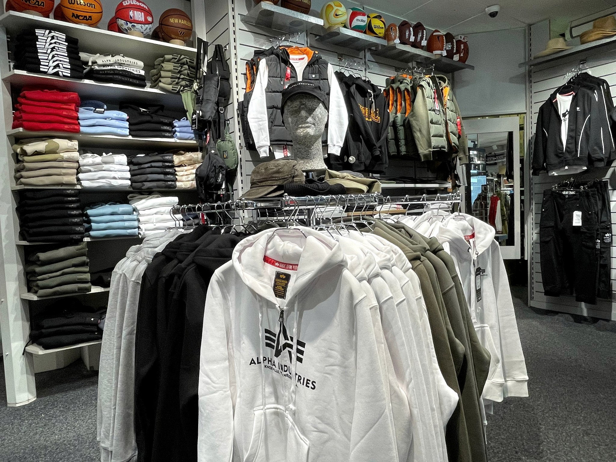 Alpha-Industries-Fläche im US SHOP Karlsruhe mit Hoodie-Ständer, Sweatshirt-Regalen und Westen