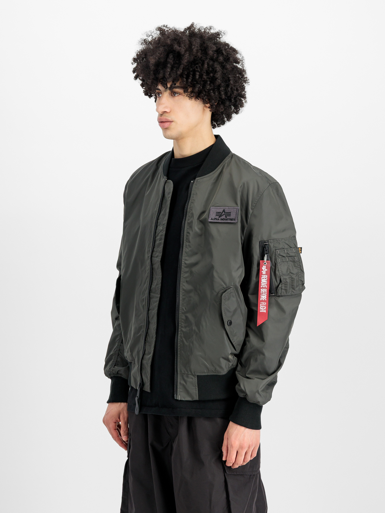 Alpha Industries MA-1 Bomberjacke in Oliv mit rotem Remove-Before-Flight-Anhänger